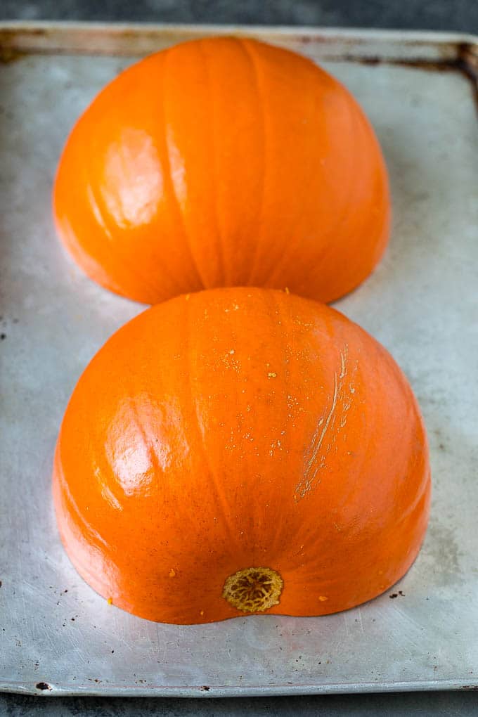 This pumpkin soup is roasted pumpkin pureed with vegetables and cream, with a generous amount of smoky bacon on top. Pumpkin halves on a sheet pan.