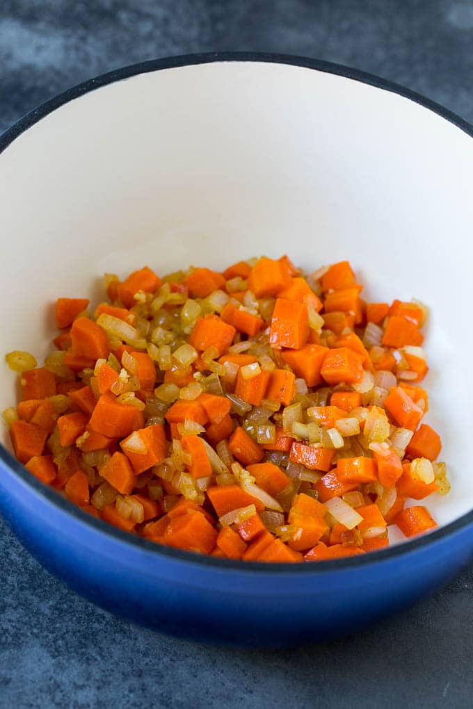 This pumpkin soup is roasted pumpkin pureed with vegetables and cream, with a generous amount of smoky bacon on top. Carrots, onions and garlic cooked in a pot.