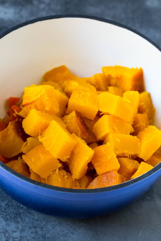 This pumpkin soup is roasted pumpkin pureed with vegetables and cream, with a generous amount of smoky bacon on top. Cubed roasted squash in a large pot.