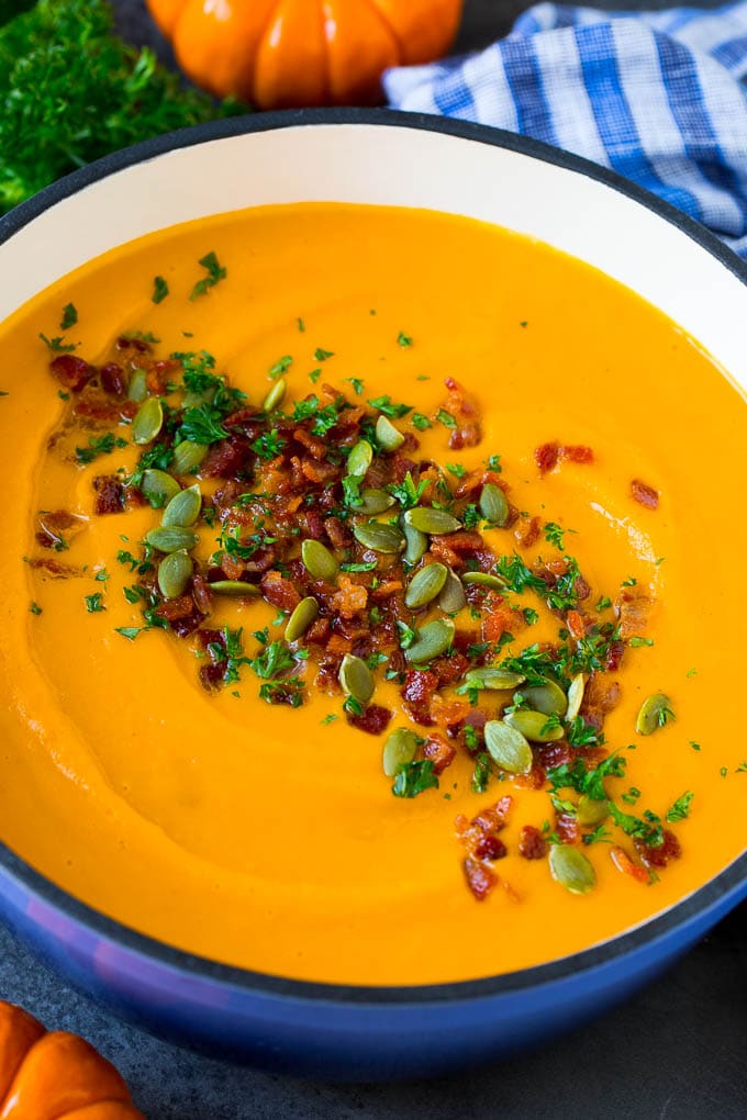This pumpkin soup is roasted pumpkin pureed with vegetables and cream, with a generous amount of smoky bacon on top. A pot of creamy pumpkin soup with bacon and herbs.