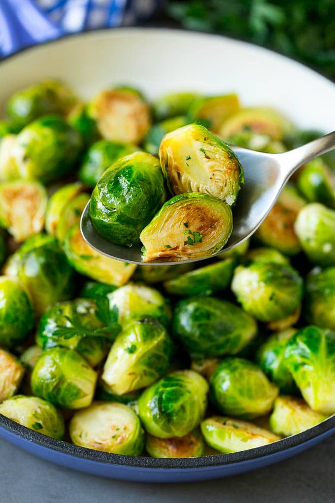 Sauteed Brussels Sprouts Recipe | Brussels Sprouts Side Dish #brusselssprouts #sprouts #veggies #sidedish #garlic #vegetarian #dinner #sadud A spoon holding up a serving of cooked brussels sprouts.