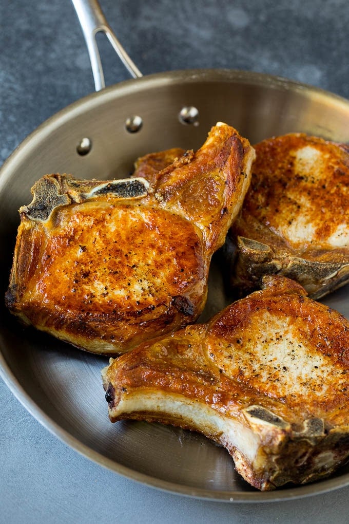 Browned pork chops in a skillet.