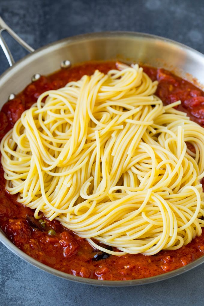 Pasta Puttanesca Recipe #pasta #tomatoes #olives #italianfood #dinner #sadud Spaghetti in a pan of tomato sauce with olives and capers.