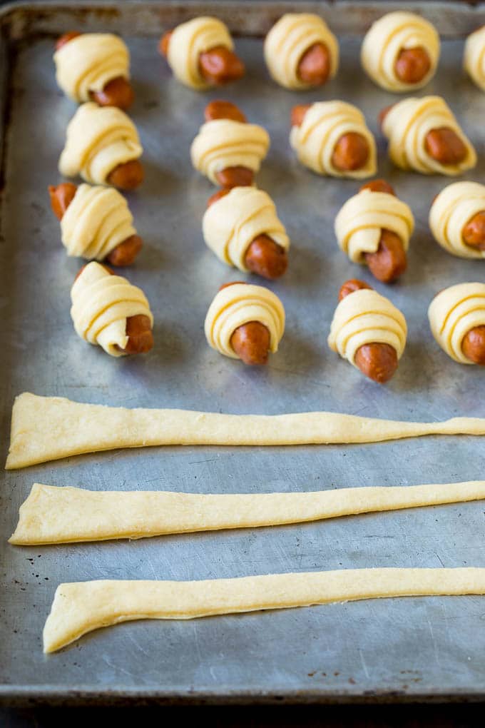 Pigs in a Blanket Recipe #hotdogs #appetizer #snack #comfortfood #sadud Strips of crescent dough on a sheet pan.
