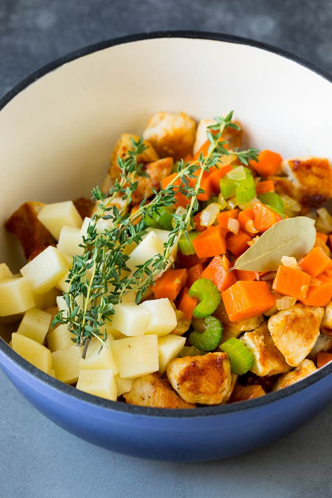 Chicken Pot Pie Soup Recipe | Chicken Soup #soup #chicken #dinner #comfortfood #sadud Ingredients such as vegetables, potatoes and herbs in a pot.