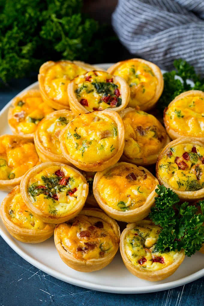 Mini Quiche Recipe #eggs #breakfast #brunch #appetizer #sadud A plate of mini quiche filled with meats, vegetables and cheeses.