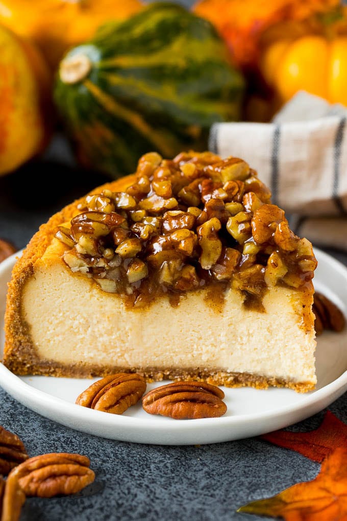 This pecan pie cheesecake is a creamy brown sugar cheesecake topped with a rich and decadent pecan sauce. A slice of pecan pie cheesecake on a serving plate.