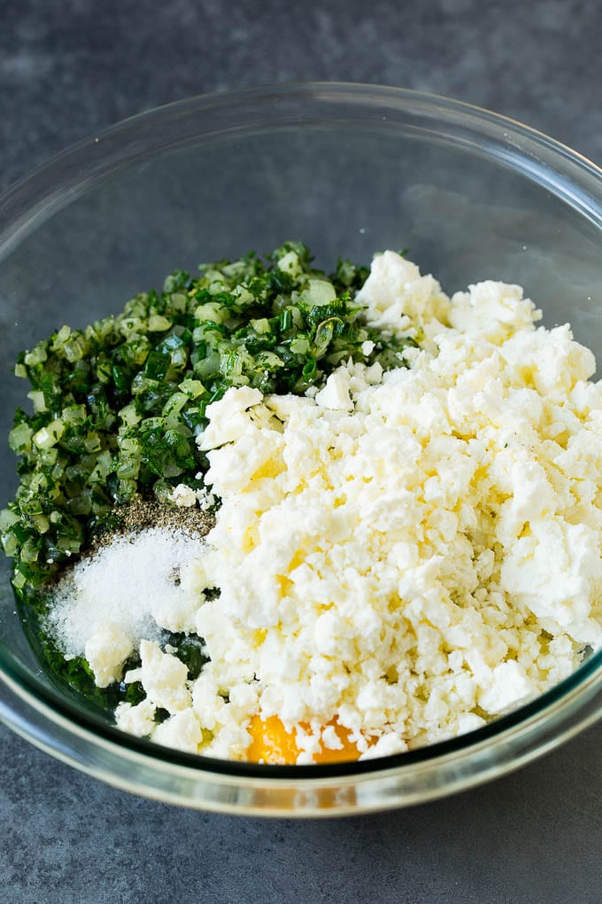 Spanakopita Recipe #appetizer #snack #spinach #cheese #sadud Spinach, onions, herbs and feta cheese in a bowl.