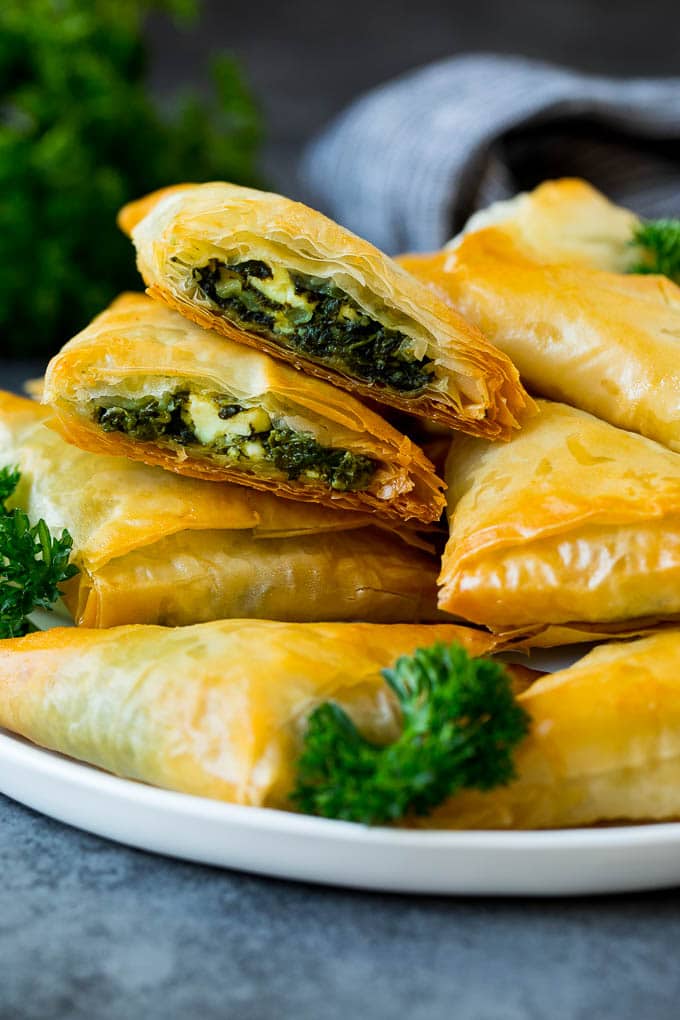 Spanakopita Recipe #appetizer #snack #spinach #cheese #sadud A plate of spanakopita with two cut in half.