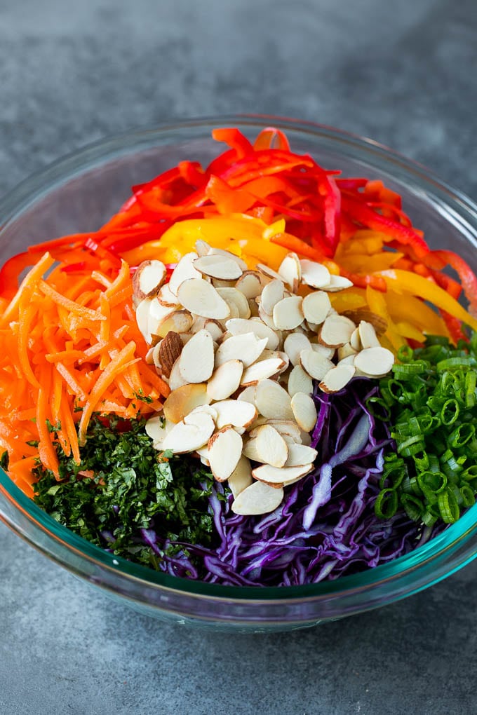 Asian Slaw Recipe #salad #slaw #sidedish #sadud Shredded cabbage, vegetables and almonds in a bowl.