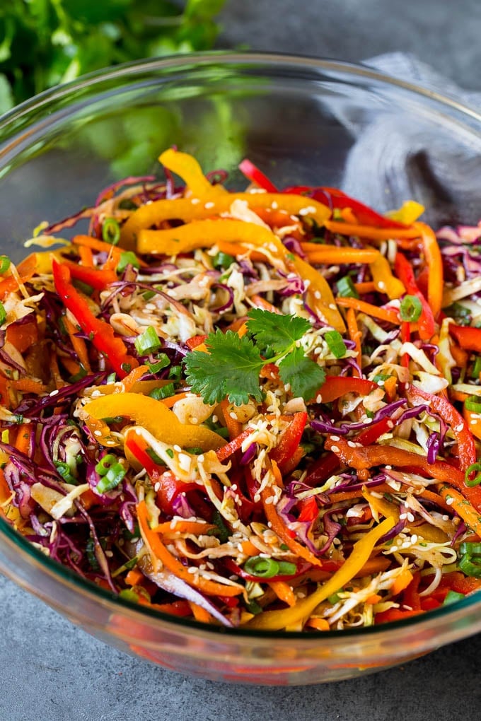 Asian Slaw Recipe #salad #slaw #sidedish #sadud A bowl of Asian slaw garnished with sesame seeds and herbs.