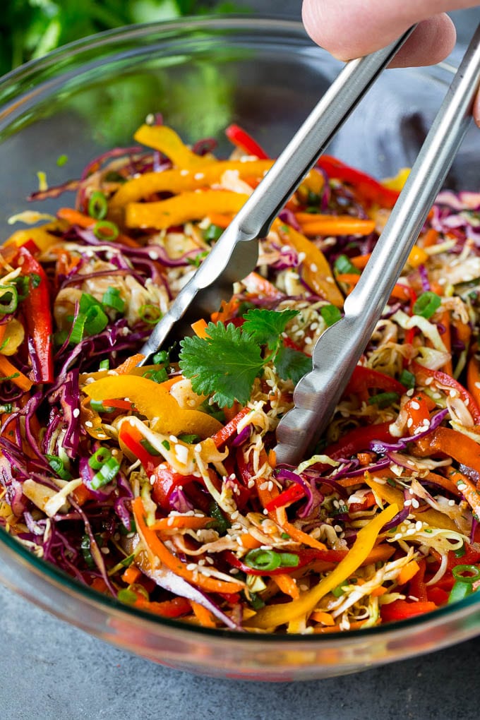 Asian Slaw Recipe #salad #slaw #sidedish #sadud Tongs serving up a portion of Asian slaw.