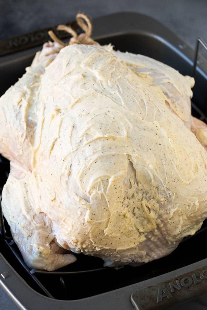 This is a complete guide on how to cook a turkey. A raw turkey coated in seasoned butter.