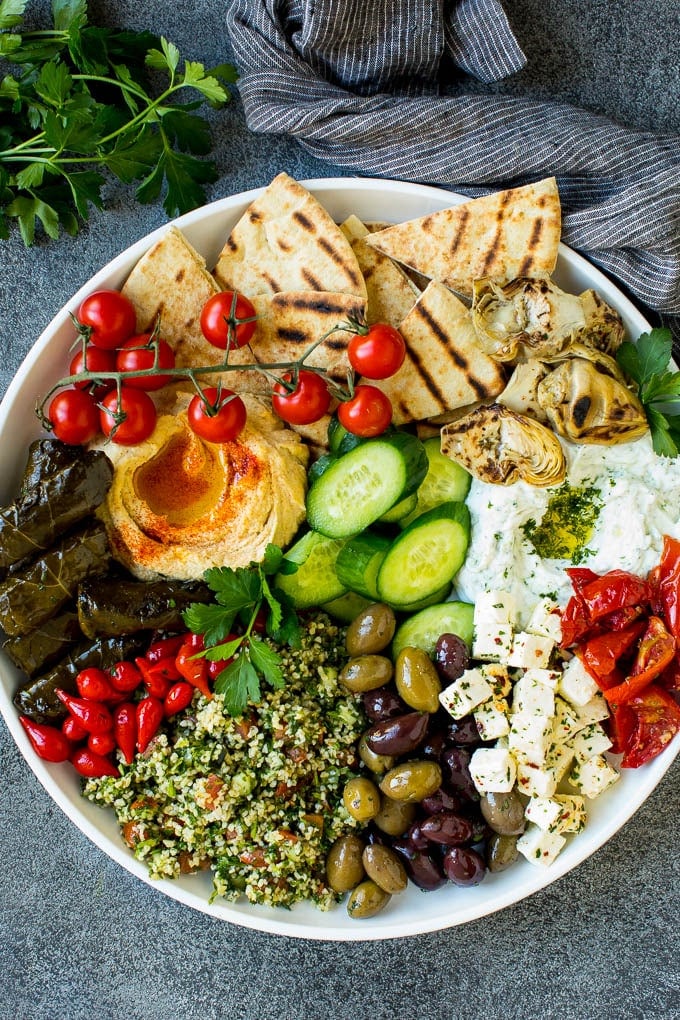 This mezze platter is filled with Mediterranean delicacies including dolmas, hummus, vegetables, pita bread and salads. #appetizer #sadud A mezze platter filled with dips, pita bread, vegetables, olives and cheese.