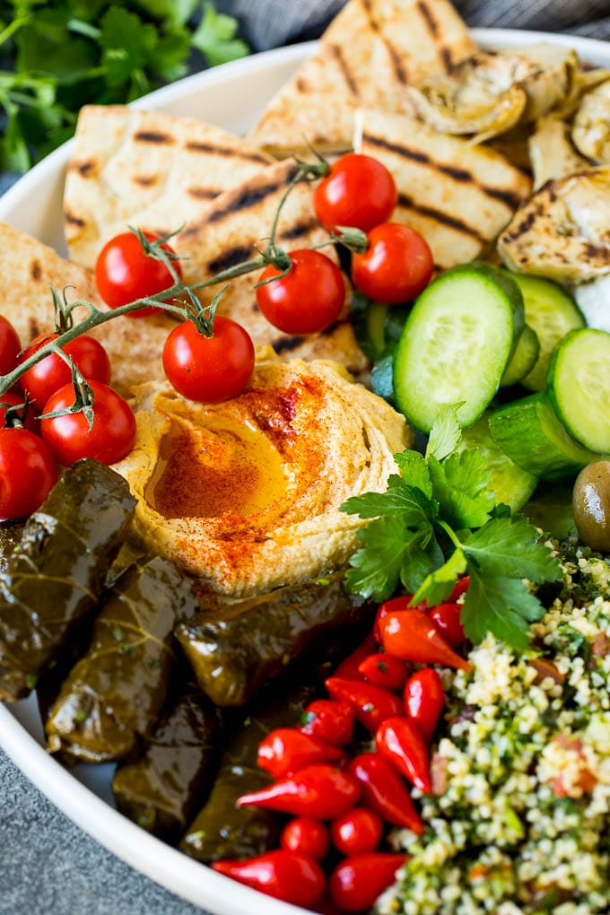 This mezze platter is filled with Mediterranean delicacies including dolmas, hummus, vegetables, pita bread and salads. #appetizer #sadud A Mediterranean mezze platter with hummus, dolmas and vegetables.