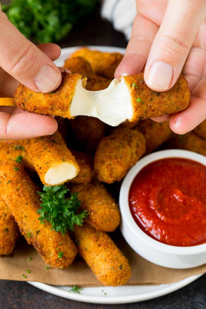 Mozzarella Sticks Recipe #cheese #appetizer #sadud A hand pulling apart mozzarella sticks.