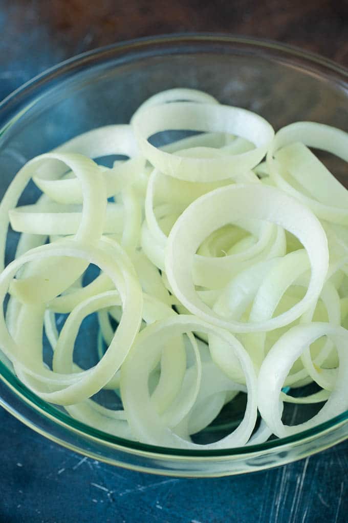 Crispy homemade onion rings that are fried in a flavorful beer batter. #onions #sadud #appetizer Raw onion slices in a bowl.