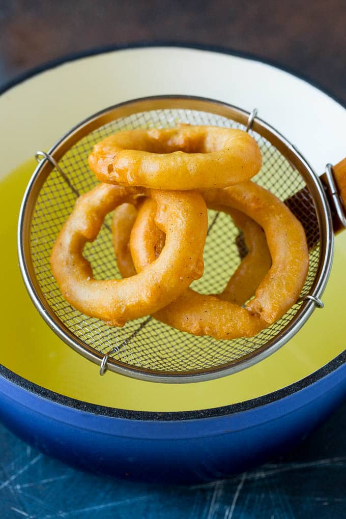 Crispy homemade onion rings that are fried in a flavorful beer batter. #onions #sadud #appetizer Fried onions coming out of a pot of oil.
