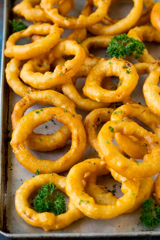 Crispy homemade onion rings that are fried in a flavorful beer batter. #onions #sadud #appetizer Beer battered onion rings on a sheet pan.