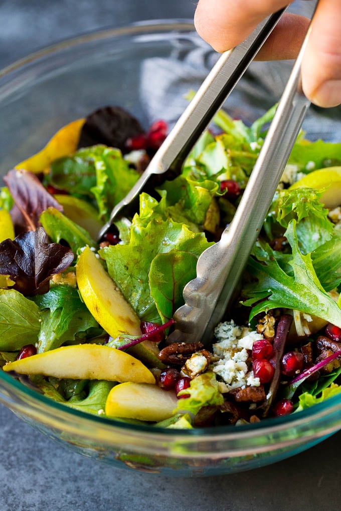 Pear Salad Recipe #salad #pears #fall #winter #dinner #sadud Tongs serving up a portion of pear salad.