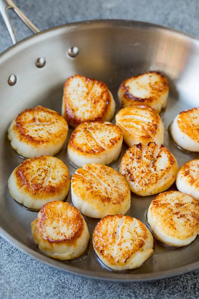 Seared scallops with a garlic and herb butter sauce. An easy and elegant dinner! #seafood #dinner #sadud Scallops cooked to golden brown in a pan.