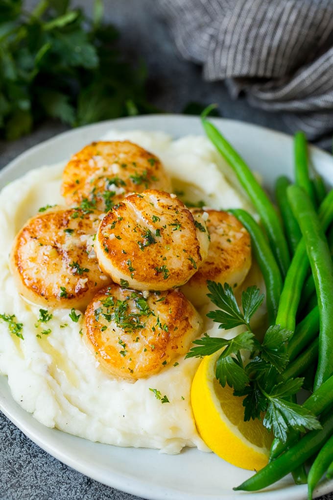 Seared scallops with a garlic and herb butter sauce. An easy and elegant dinner! #seafood #dinner #sadud Seared scallops served with mashed potatoes and green beans.