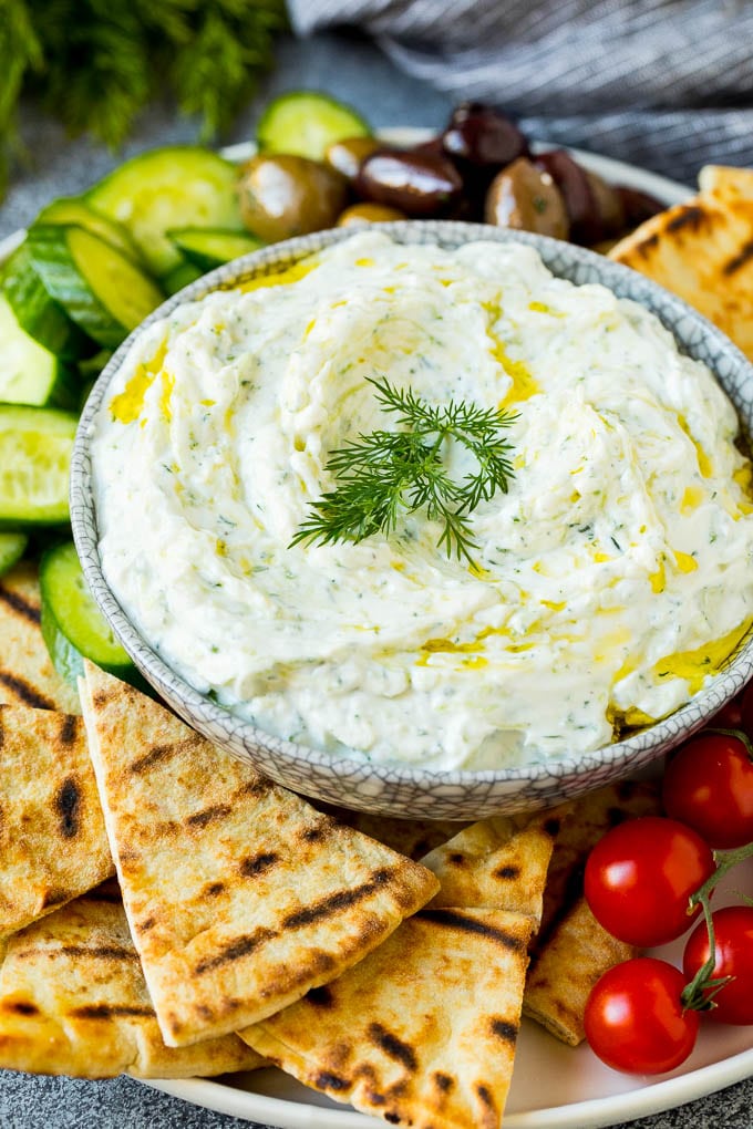 The best homemade tzatziki sauce with cucumber and herbs mixed into Greek yogurt. #appetizer #sadud A bowl of tzatziki served with pita bread and vegetables.