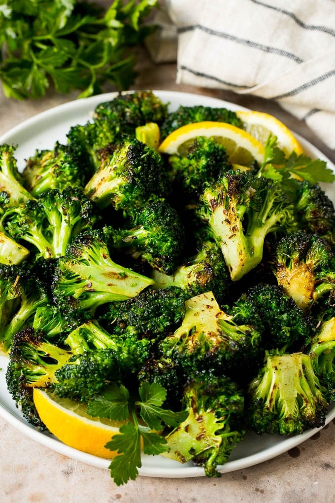 Grilled broccoli is packed with flavor and is a colorful and healthy side dish! #broccoli #sadud Grilled broccoli topped with parsley and garnished with lemon wedges.