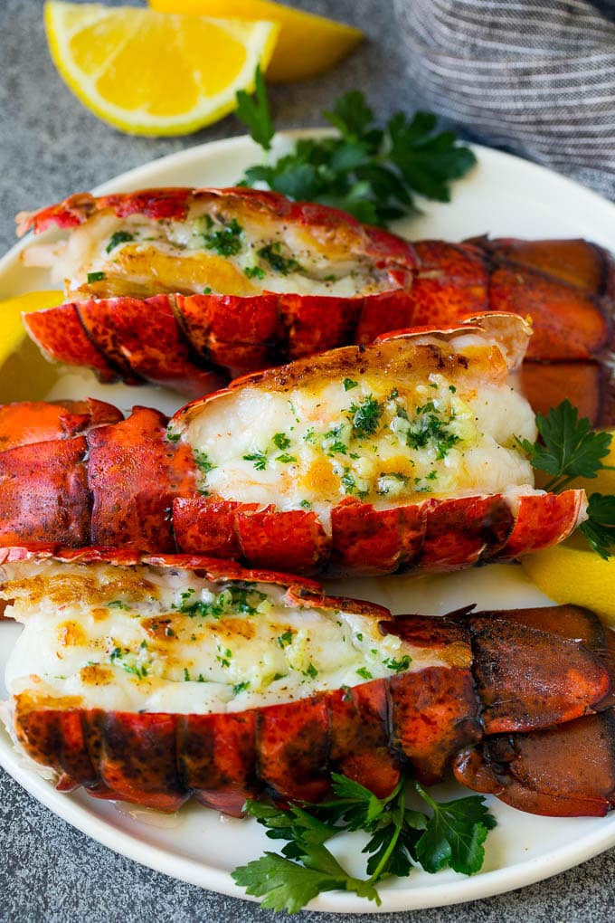 Grilled lobster tail drizzled with garlic butter is an easy and elegant dinner option. #lobster #sadud Grilled lobster tail topped with garlic butter and garnished with lemon and parsley.