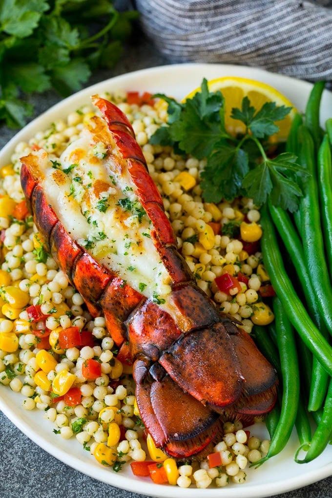 Grilled lobster tail drizzled with garlic butter is an easy and elegant dinner option. #lobster #sadud Grilled lobster tail served with couscous and green beans.