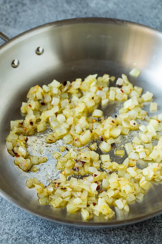 Sauteed kale flavored with olive oil and garlic, a quick and easy side dish! #kale #sadud Sauteed onions in a skillet.