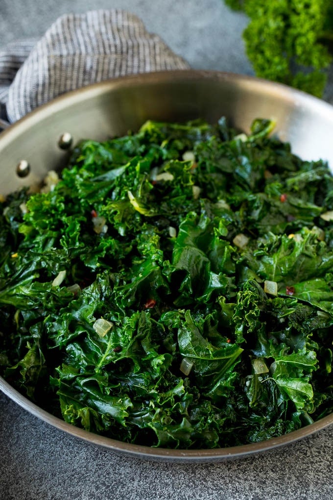 Sauteed kale flavored with olive oil and garlic, a quick and easy side dish! #kale #sadud Cooked kale with olive oil, onions and garlic.