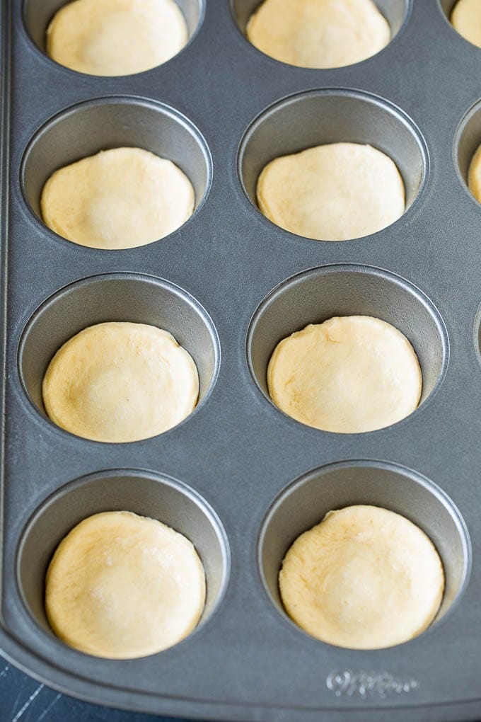 Mini pizzas topped with pepperoni are a fun and easy appetizer option. #pizza #sadud #appetizer Dough circles pressed into muffin cups.