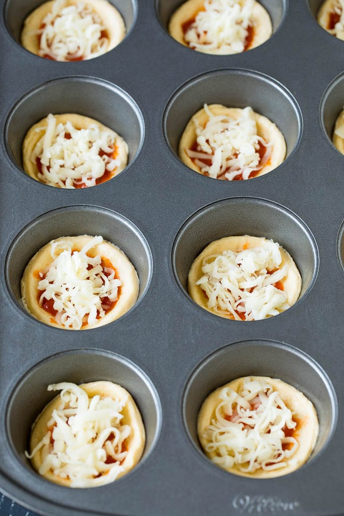 Mini pizzas topped with pepperoni are a fun and easy appetizer option. #pizza #sadud #appetizer Circles of dough topped with pizza sauce and shredded cheese.