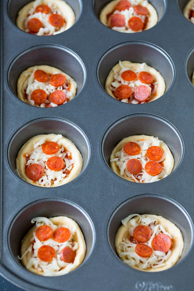 Mini pizzas topped with pepperoni are a fun and easy appetizer option. #pizza #sadud #appetizer Dough topped with sauce, cheese and mini pepperoni.