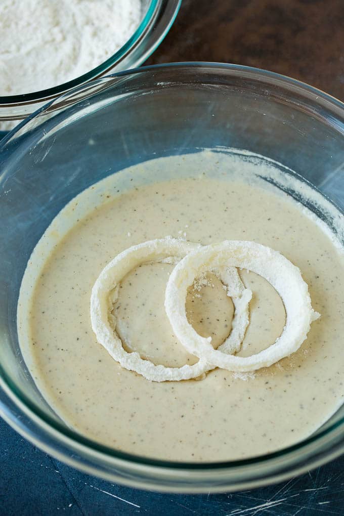 Crispy homemade onion rings that are fried in a flavorful beer batter. #onions #sadud #appetizer Floured onions in a bowl of beer batter.