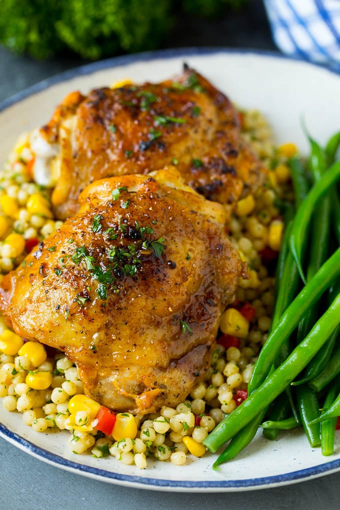 These baked chicken thighs are coated in olive oil, garlic and herbs, then oven roasted until golden brown. Baked chicken thighs served over couscous with a side of green beans.
