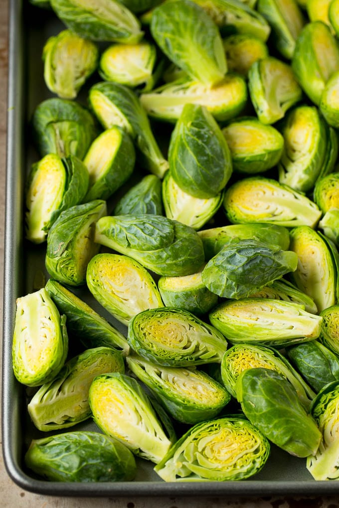Balsamic brussels sprouts are roasted with bacon, then topped with a drizzle of balsamic glaze. Halved sprouts on a sheet pan.