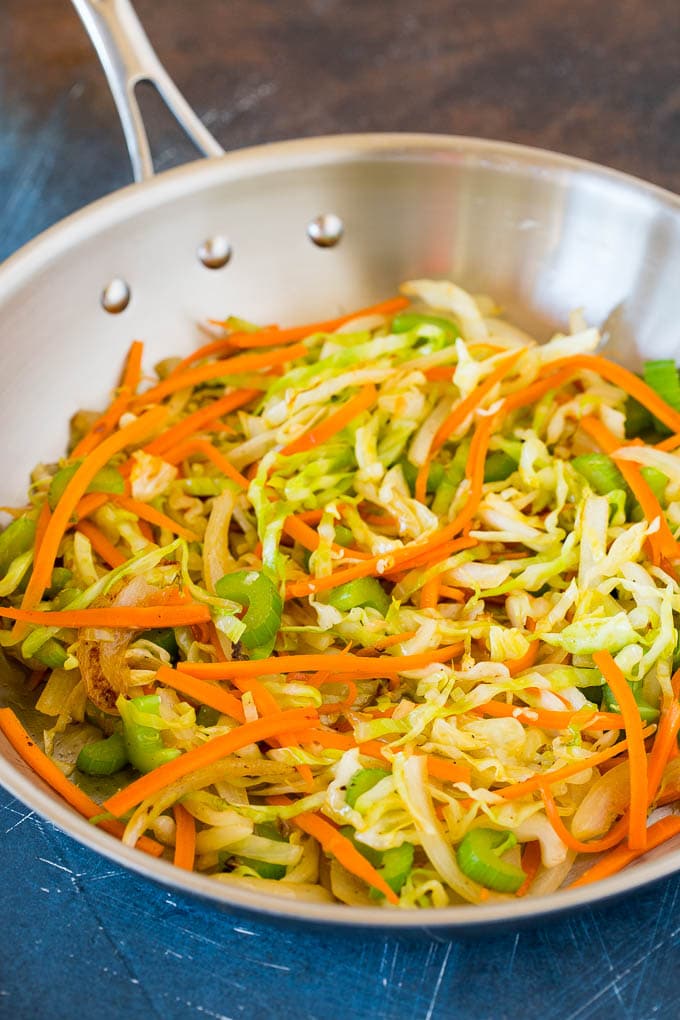 This beef lo mein is stir fried steak and vegetables tossed with egg noodles in a savory sauce. Carrots, celery and cabbage cooked in a pan.