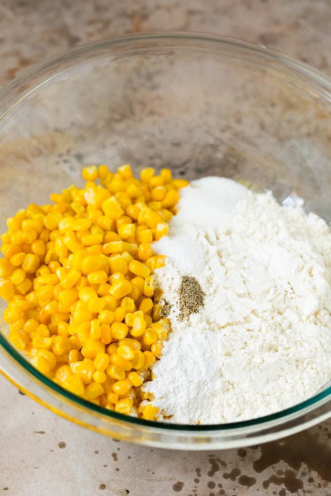 These crispy corn fritters are easy to make and are the perfect appetizer or lighter main course. #corn #sadud Flour, corn and seasonings in a mixing bowl.