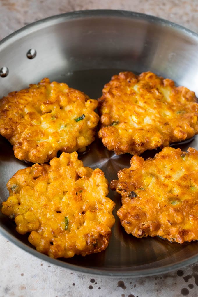 These crispy corn fritters are easy to make and are the perfect appetizer or lighter main course. #corn #sadud Corn cakes in a pan of oil.
