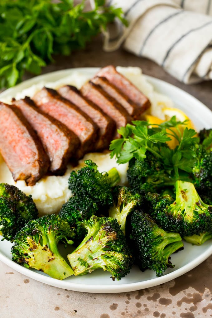 Grilled broccoli is packed with flavor and is a colorful and healthy side dish! #broccoli #sadud Grilled broccoli on a plate with steak and mashed potatoes.