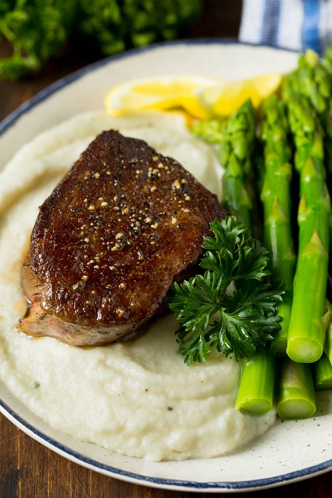 These cauliflower mashed potatoes are mixed with butter, cream and seasonings to make a super delicious side dish that's low in carbohydrates. Cauliflower mashed potatoes on a plate with steak and asparagus.