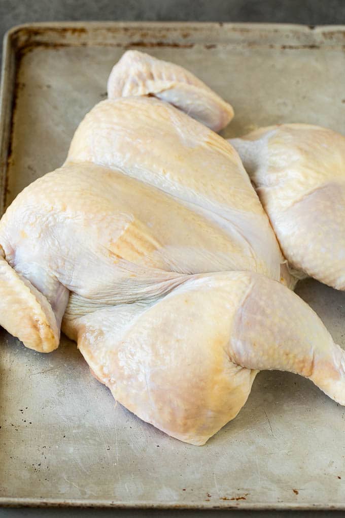 This spatchcock chicken is tender, juicy and cooks quickly, the perfect easy dinner! A chicken laid out flat on a sheet pan.