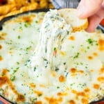 A slice of bread scooping up a serving of spinach artichoke dip.