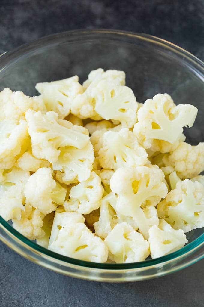 This cauliflower casserole is cooked cauliflower florets tossed in a homemade cheese sauce, then mixed with bacon and green onions and baked to golden brown perfection. Cooked cauliflower florets in a bowl.