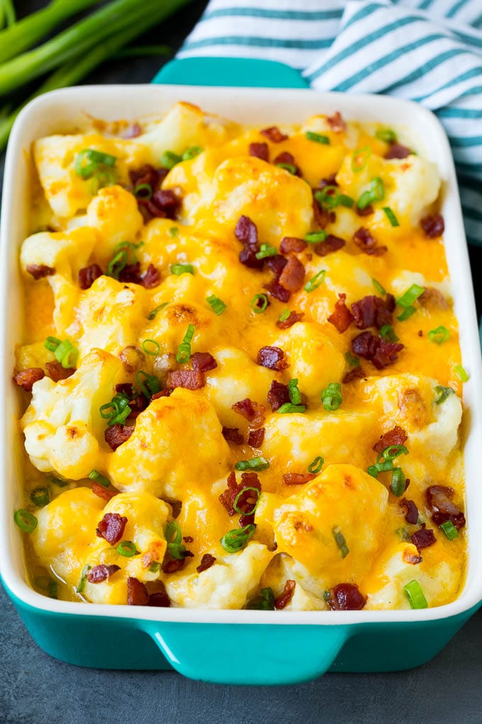 This cauliflower casserole is cooked cauliflower florets tossed in a homemade cheese sauce, then mixed with bacon and green onions and baked to golden brown perfection. Cauliflower casserole topped with melted cheese, bacon and green onions.