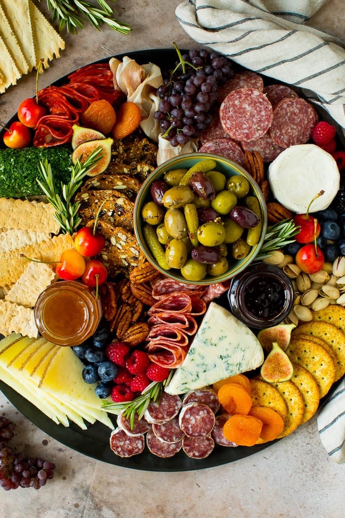 A complete guide on how to put together the best charcuterie board, with a selection of meats, cheeses, crackers, fruit, veggies and other snack foods. A charcuterie board filled with meats, cheeses, crackers, fruit and nuts.
