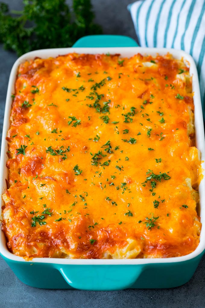 These cheesy potatoes are diced potatoes tossed in a creamy blend of sour cream, butter and cheese, then baked to golden brown perfection. Cheesy potatoes in a casserole dish topped with melted cheddar and parsley.