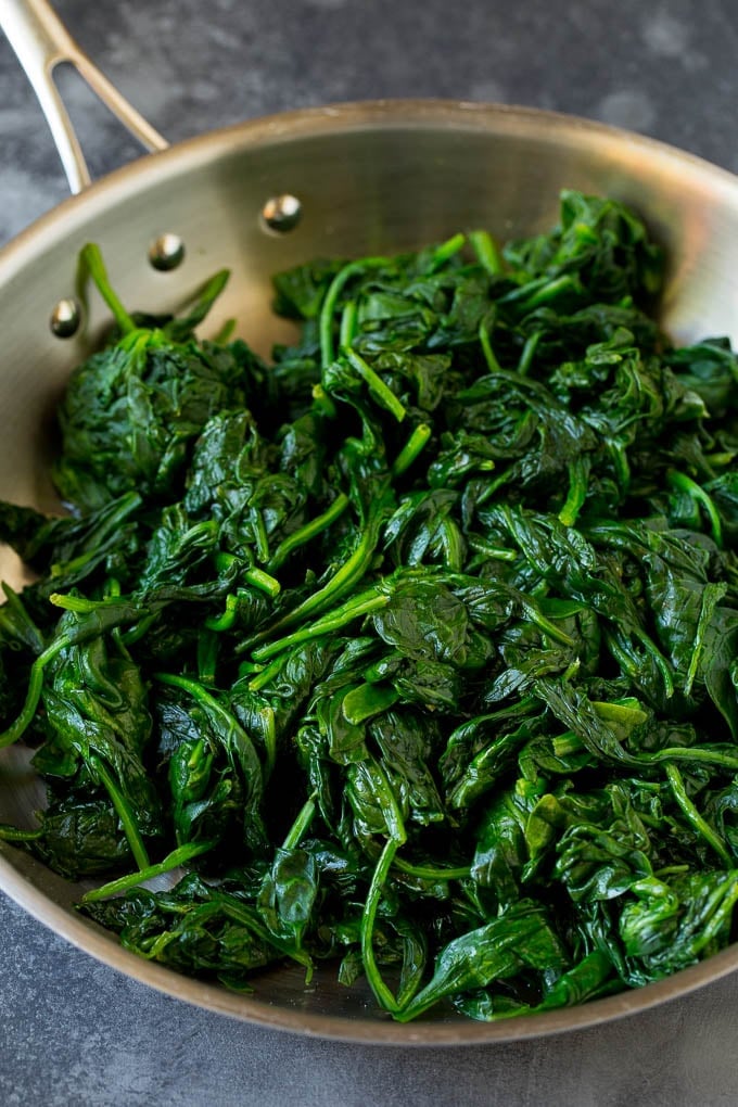 This creamed spinach is fresh sauteed spinach leaves in a flavorful cream sauce with parmesan cheese. Cooked greens in a pan.